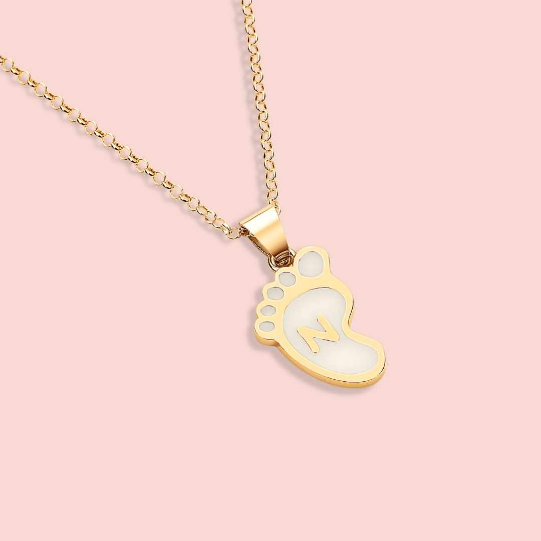 El colgante pie de leche con inicial materna personalizada simboliza las primeras huellas de tu bebé y la huella imborrable que deja en tu vida.